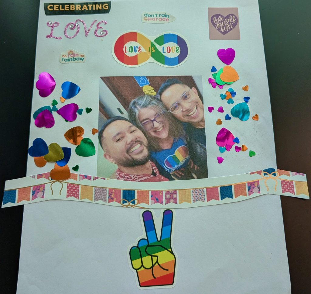 Collage on a white background contains an image of two men and a woman smiling, colourful hearts, and stickers and text that say "Celebrating Love," "No rain, no rainbow," "don't rain on my parade," "Love is Love," and "Love Yourself First." The piece also has a party banner that spans the lower third of the collage and a rainbow sticker in the shape of a hand making the peace sign.